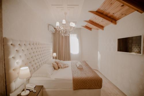 a white room with a bed and a chandelier at Green House Hotel & Restaurant in Tirana