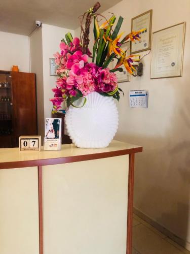 a white vase filled with pink flowers on a table at Hotel Plaza in Craiova