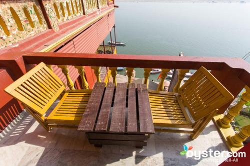 a wooden bench sitting on a balcony next to the water at Ganpati Guest House in Varanasi