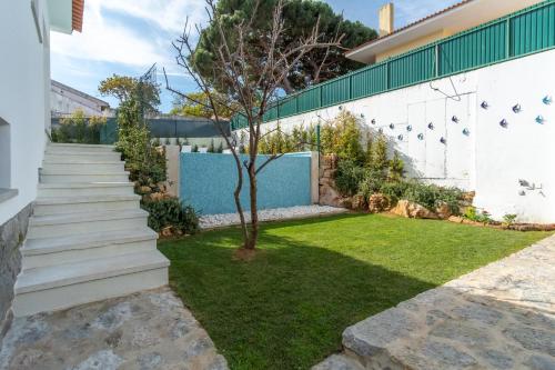 a garden with stairs and a small tree next to a wall at Casa em Cascais in Cascais