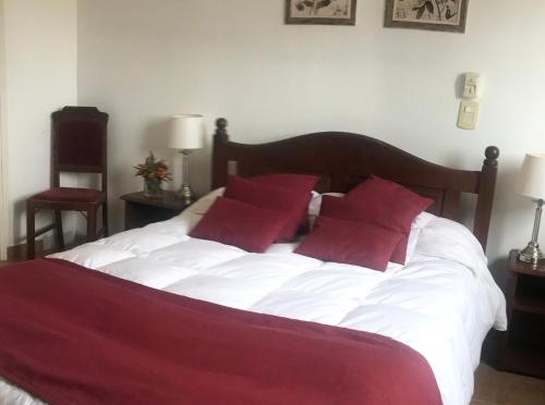 a bedroom with a white bed with red pillows at Hotel Olijnyk in Rosario del Tala