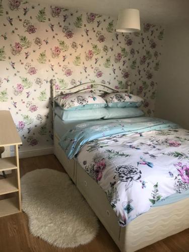 a bedroom with a bed with flowers on the wall at The Cottage, cosy 2 bedroom pet friendly perfect for contractors free secure parking,CCTV in Leeds