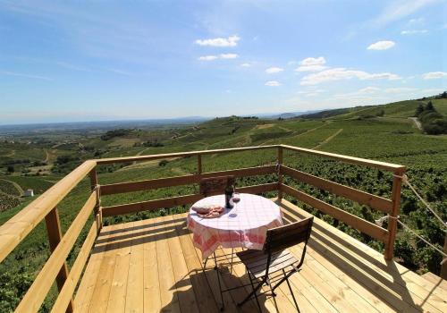 une table et une chaise sur une terrasse en bois avec vue dans l'établissement Tiny house au cœur du vignoble beaujolais, à Fleurie