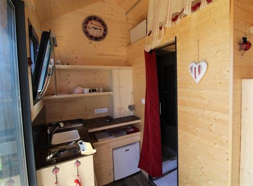 - une cuisine dans une petite maison avec une horloge sur le mur dans l'établissement Tiny house au cœur du vignoble beaujolais, à Fleurie