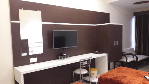 um quarto com uma televisão na parede em Hotel Zenith em Surat