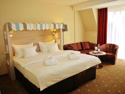 ein Hotelzimmer mit einem großen Bett und einem Sofa in der Unterkunft Landhaus Am Grün in Kühlungsborn