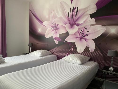 トロワにあるAppart du cirque centre historiqueのベッド2台(壁に白と紫の花を飾る)