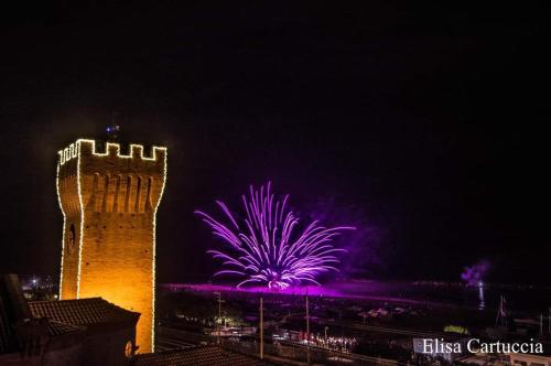 uno spettacolo di fuochi d'artificio dietro un edificio con torre di La Casa di Sandra a Porto Potenza Picena