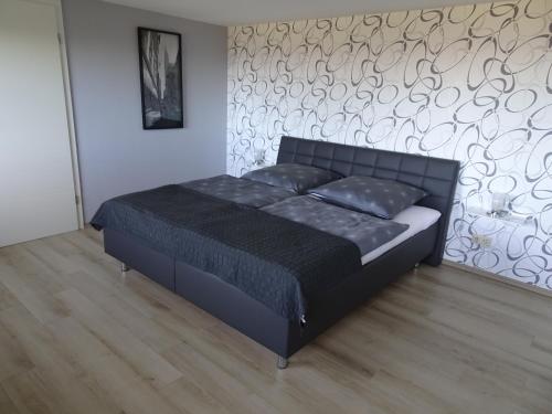 a black bed in a room with a wall at Ferienwohnung Hoffmann in Osburg
