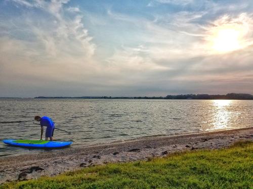 a man standing on a paddle board in the water at Sandaway Suites & Beach in Oxford