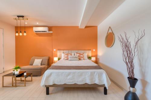 a bedroom with orange walls and a bed and a chair at Sunshine SXM Studios in Grand Case