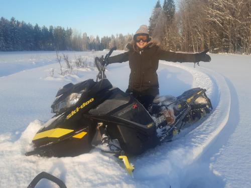a woman standing next to a snowmobile in the snow at Holmens Boende och Event in Luleå