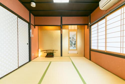 einen leeren Flur mit einem Tisch in einem Zimmer mit Fenstern in der Unterkunft Kyooyado Muromachi in Kyoto