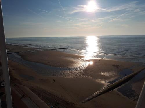a view of a beach with the sun reflecting in the water at Charmant appartement met frontaal zeezicht in Middelkerke