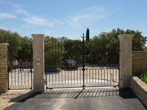 a gate to a driveway with a car behind it at Domaine de l'Enclos in Gordes