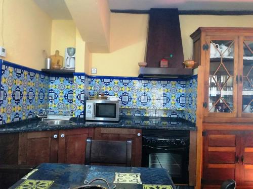 - une cuisine avec du carrelage bleu et blanc sur le mur dans l'établissement Casa de Aldea La Pescal, à La Pescal