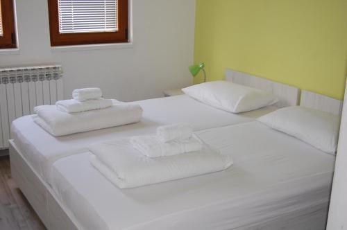two beds with white sheets and towels on them at Pansion Fočin Han in Sarajevo