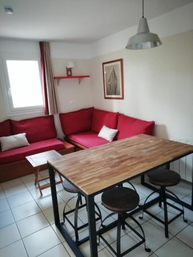 ein Wohnzimmer mit einem roten Sofa und einem Holztisch in der Unterkunft LES GRANDS PINS in Carcans