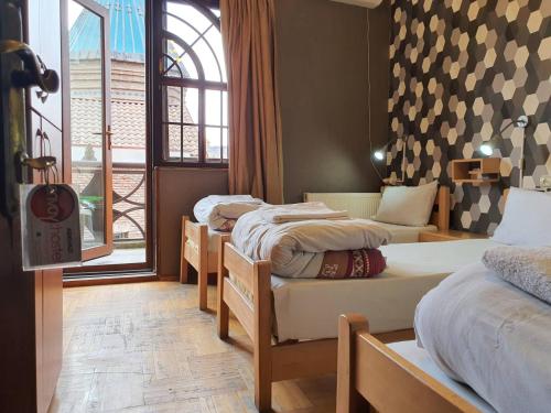 a room with four beds and a window and a room with at Envoy Hostel in Tbilisi City