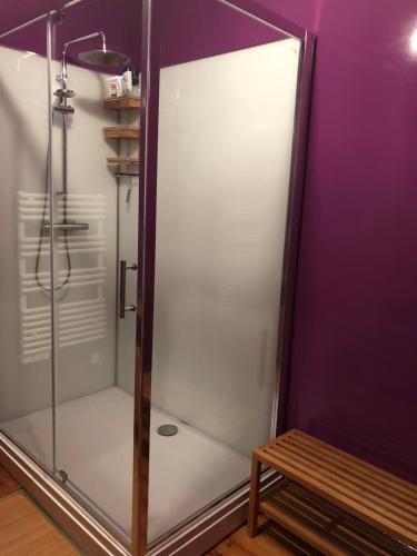 a shower with a glass door next to a wooden bench at Chez Savary in Varzay