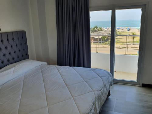 a bedroom with a bed and a view of a beach at Hosteria Palmetto in Playas