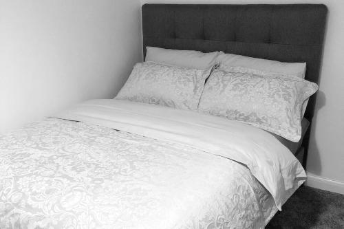 - un lit blanc avec une tête de lit et des oreillers noirs dans l'établissement Flat 2 - Entire Modern Two Bedrooms home with en-suite & free parking close to QMC, City centre and Notts uni - Self check in, à Nottingham