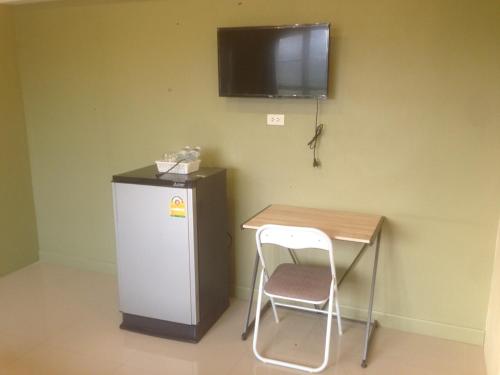 a small table with a chair next to a small refrigerator at Kim Casa in Nakhon Sawan