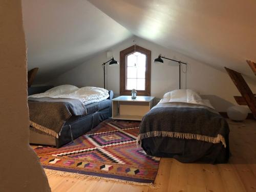 a attic room with two beds and a window at Oxelbacka cottage in Enköping