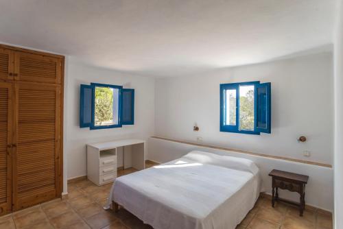 um quarto com uma cama, uma secretária e 2 janelas em CASA PATRICIA Cala Saona em Cala Saona