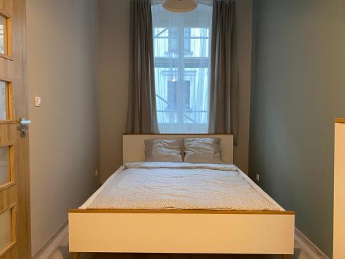małą sypialnię z łóżkiem z oknem w obiekcie Apartament URBAN JUNGLE! w Poznaniu