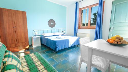 a blue bedroom with a bed and a table with a bowl of fruit at Residence Contrada Schite in Presicce