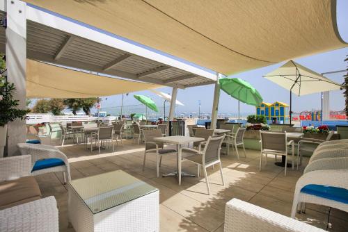 un patio esterno con tavoli, sedie e ombrelloni di San Marco a Marotta