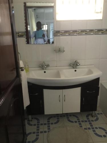 a bathroom with a sink and a person in the mirror at Kigezi Gardens Inn in Kabale