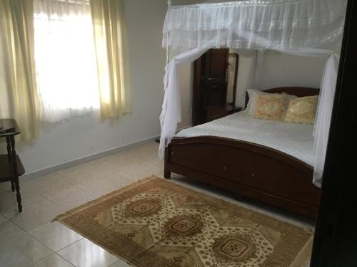 a bedroom with a bed with a canopy and a rug at Kigezi Gardens Inn in Kabale
