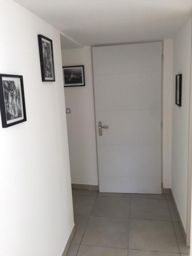 a hallway with a white door and pictures on the wall at MONTALIEU SEJOUR Rez de jardin Les jonquilles - 1 à 4 PERS - PROX CNPE BUGEY - VALLEE BLEU - VIA RHONA in Montalieu-Vercieu