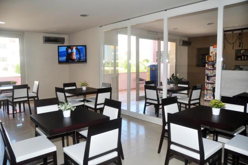 un restaurant avec des tables et des chaises ainsi qu'une télévision murale. dans l'établissement Hotel La Punta, à Otrante