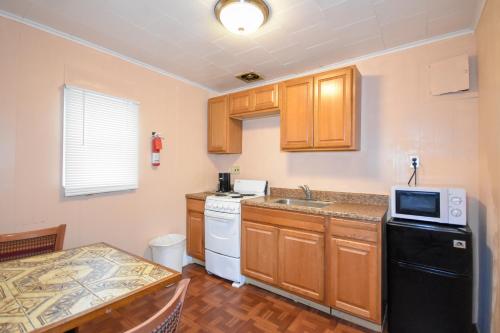 a kitchen with wooden cabinets and a black refrigerator at Monticello Inn- Framingham/ Boston in Framingham