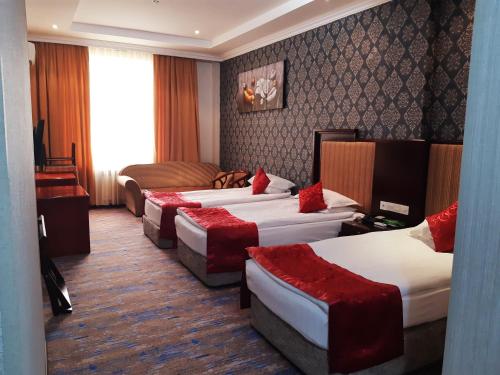 a hotel room with four beds with red pillows at Royal Hotel in Baku