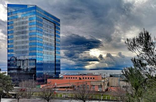 a tall glass building in a city under a cloudy sky at Apartment Gervais Rijeka in Rijeka