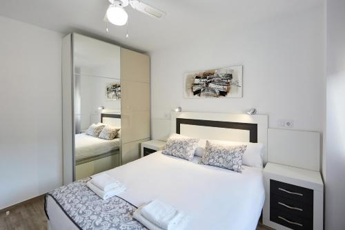 1 dormitorio con cama blanca y espejo en Sonrisa Apartments, en Benidorm