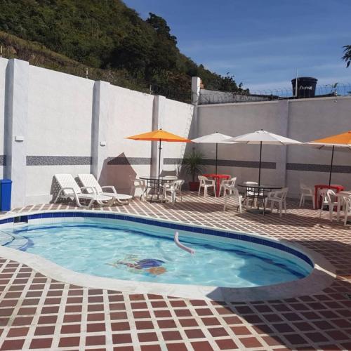 a swimming pool with chairs and tables and umbrellas at Hotel Emperador in Barbosa