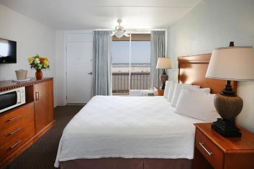 ein Hotelzimmer mit einem großen Bett und einem Fenster in der Unterkunft Aquarius Oceanfront Inn in Wildwood