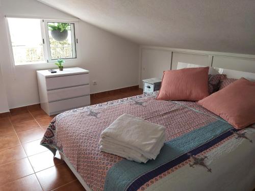 een slaapkamer met een groot bed met roze kussens bij Tabua Village Nature Lovers & Sea #5 in Ribeira Brava