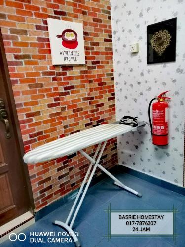 a bench next to a brick wall with a fire extinguisher at Basrie Villa Pagoh - Mini Cinema , Karaoke , Private Pool , WiFi , NetFlix in Muar