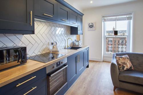 a kitchen with blue cabinets and a couch in a room at Host & Stay - Little Acorn Apartment in Whitby