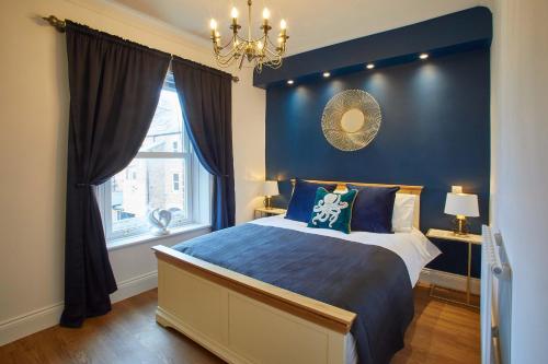 a blue bedroom with a bed and a window at Host & Stay - Little Acorn Apartment in Whitby