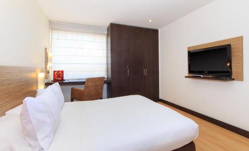 a hotel room with a bed and a flat screen tv at Scala 68 in Bogotá