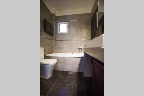 een badkamer met een bad, een toilet en een wastafel bij A Stylish Apartment In The Center Of Kastoria in Kastoria