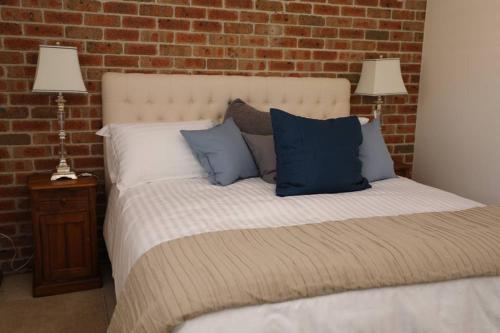 a bed with blue pillows and a brick wall at Pacific Palms Thirroul Beach NSW in Thirroul