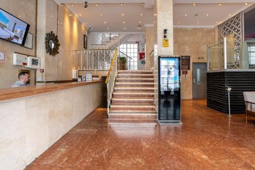 a lobby with a staircase and a man at a counter at Hotel Torremolinos Centro in Torremolinos